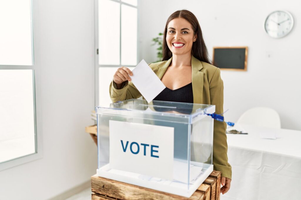 Smiling woman placing a ballot in a vote box
